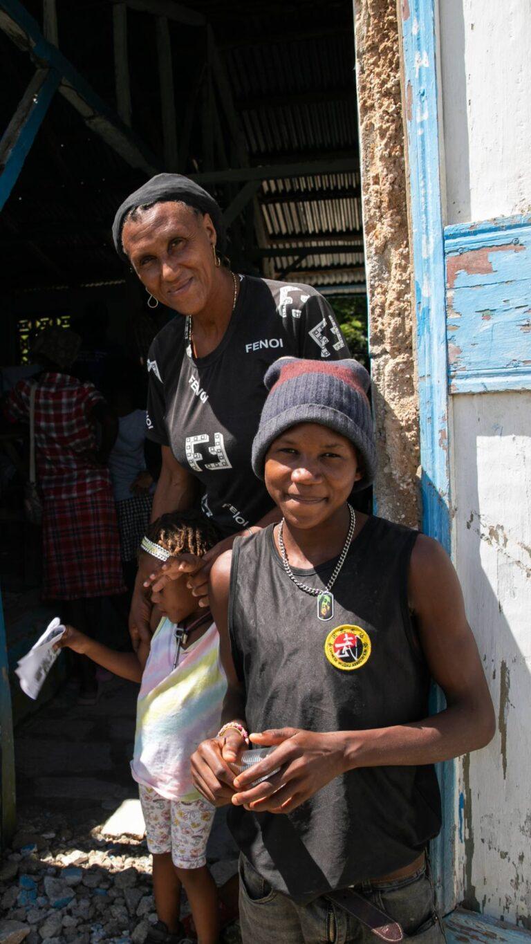 CLINIQUE MOBILE à Almande (au nord de Petit Goave), à ​​2 heures de route principale, en empruntant une route rocailleuse et escarpée. Bertino (surnommé Sava), 17 ans, avec sa petite sœur, Rayley (5 ans) et sa mère, Mirleine. 2023 Haiti © Nadia Todres