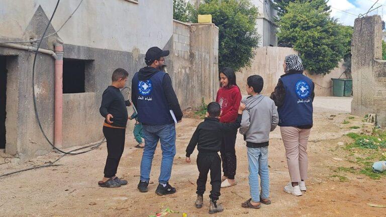 Burqin, West Bank - Feb 2025 Two MdM staff members are discussing with a group of children outside in Burqin. They are Palestinian refugees / displaced people from Jenin camp. Their families struggle daily as they continue to face displacement, insecurity, and uncertainty amid escalating violence. Families who have lost their homes and livelihoods are forced to seek shelter in overcrowded conditions, carrying the weight of trauma and fear. Despite these harsh realities, their resilience and dignity remain evident, especially in the determination of parents to protect their children and rebuild some sense of normalcy.