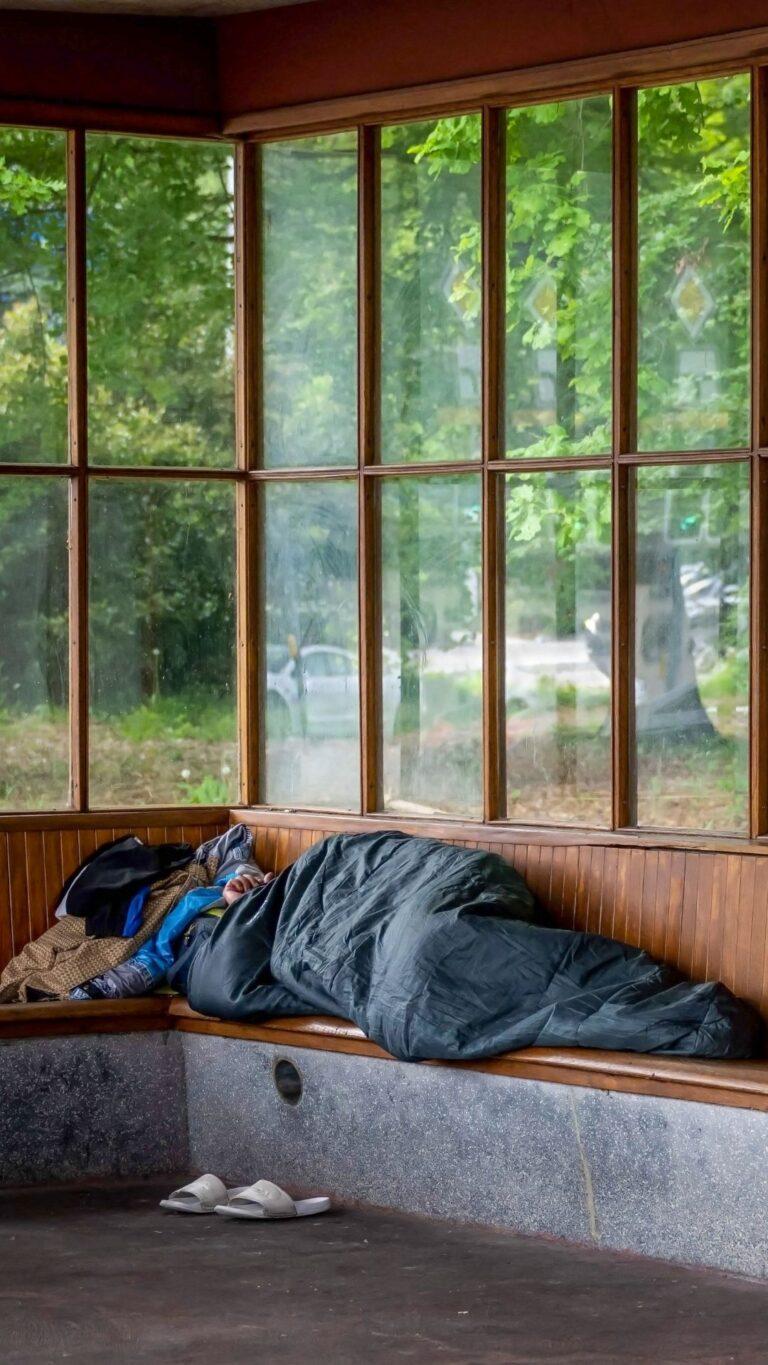 Une personne sans-abri dort dans un abri-bus, Suisse, 2023. © KEYSTONE/AFP/FABRICE COFFRINI