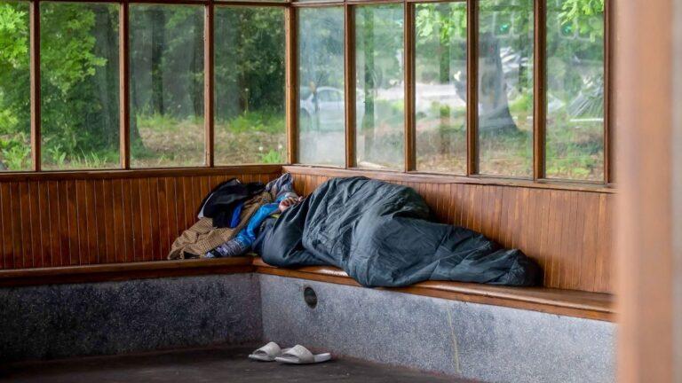 Une personne sans-abri dort dans un abri-bus, Suisse, 2023. © KEYSTONE/AFP/FABRICE COFFRINI